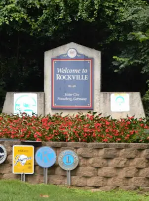 The iconic Welcome to Rockville entrance sign surrounded by flowers, signaling premium Thai massage and bodywork services for Rockville, MD residents from Spa65